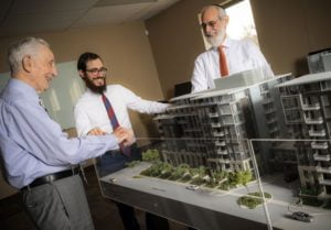 Smiling Businessmen in Suits Looking at Model Apartment Complex